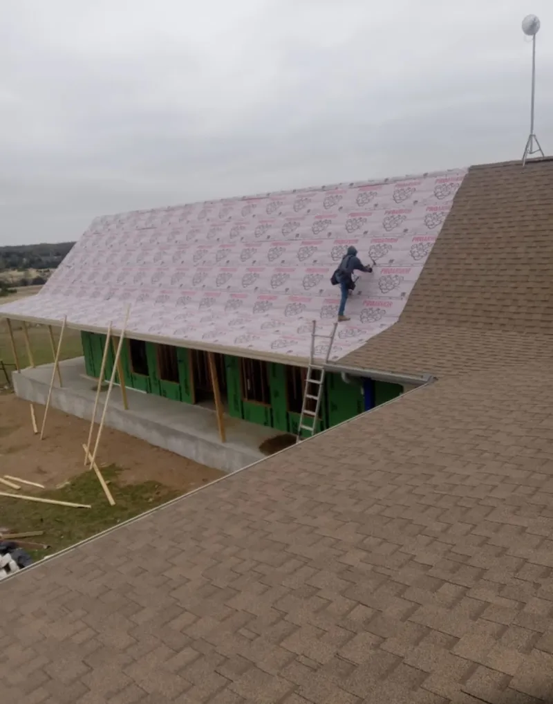 Worker preparing underlayment for a metal roof installation in McDonough